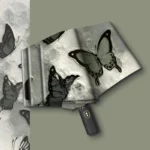 Parapluie pliant automatique avec motif papillons noir sur fond clair, poignée ergonomique et design élégant, idéal par tous les temps.