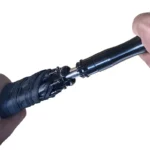 Parapluie canne glamour noir ouvert, détails élégants de la poignée et mécanisme d'ouverture, idéal pour un style raffiné.