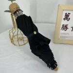 Parapluie cloche dentelle noir élégant, plié sur une table, décoré d'un support en métal doré et cadre photo en arrière-plan.