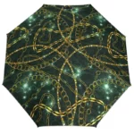Parapluie femme glamour avec motif chaînes dorées sur fond vert foncé, combinant élégance, style artistique et tendance moderne.