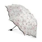 Parapluie pliable femme avec motif floral rouge sur fond blanc, compact et élégant, idéal pour une protection stylée contre la pluie.