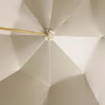 Parapluie homme luxe beige avec tige dorée, design élégant, vue intérieure symétrique, idéal pour un style raffiné et intemporel.