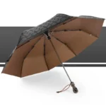 Parapluie homme robuste avec toile noire à motifs, intérieur marron élégant. Accessoire stylé et pratique pour affronter la pluie.