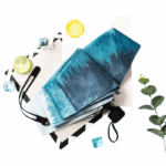 Parapluie dégradé bleu imperméable, design chic, avec citron, glaçons, plante verte sur fond graphique noir et blanc.