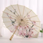 Parapluie japonais chic avec motifs fleurs de cerisier, structure en bambou élégante, design artistique raffiné, idéal pour la pluie.