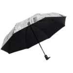 Parapluie automatique noir avec imprimé journaux, élégant et pratique, idéal pour se protéger de la pluie tout en restant stylé.