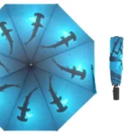 Parapluie compact bleu motifs requins ouvert et plié, design original et pratique pour une protection stylée contre la pluie.