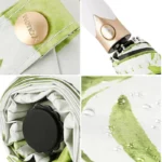 Parapluie pliant chic avec motifs verts, bouton doré, poignée élégante, ruban raffiné et gouttes de pluie sur le tissu.