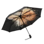 Parapluie pliant léger noir avec motif artistique crème, compact et design unique, idéal pour toutes les saisons.