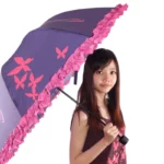 Parapluie vintage avec motifs papillons roses et bordure frisée, élégant et pratique pour affronter la pluie avec style.