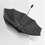 Parapluie tempête noir ouvert avec lumières LED, design robuste et élégant, parfait contre les intempéries, suspendu sur fond blanc.