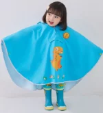 Enfant en poncho bébé léger motif dinosaure bleu, parfait pour la pluie, issu de la collection [Collection], confort et style assurés.