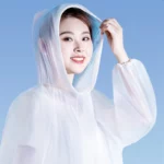 Poncho pluie de voyage 4 pièces, transparent avec capuche, idéal pour vos déplacements, présenté par un modèle souriant.