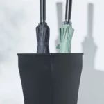 Porte parapluie classique noir avec deux parapluies pliés, noir et vert, idéal pour organiser vos accessoires avec style.