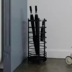 Porte-parapluie de luxe en métal noir, design élégant, idéal pour organiser vos parapluies pliés près d'un mur.
