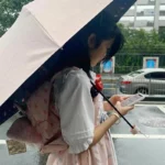 Femme sous la pluie avec un parapluie rose, sac à dos pratique, mode légère, idéal pour la collection Porte parapluie sac à dos.