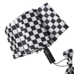 Parapluie anglais femme pliable motif damier noir et blanc, élégant et compact, parfait pour les journées pluvieuses.