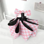 Parapluie anglais femme à motif damiers rose-blanc, élégant avec nœud décoratif, idéal pour allier style et protection contre la pluie.