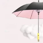 Parapluie coupe-vent noir et rose au manche jaune, élégant et robuste, idéal par mauvais temps, présenté sur un fond pastel.