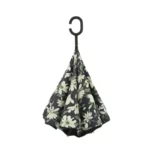 Parapluie inversé chic avec motif floral sur fond sombre, suspendu à une branche noire en S, idéal pour style et pluie.