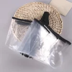 Parapluie transparent résistant avec poignée noire sur plat en osier, élégant et pratique pour la pluie avec vue dégagée.