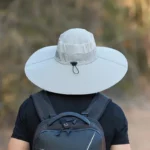 Homme de dos en nature avec chapeau de pluie gris anti-UV à larges bords imperméable taille E27, idéal protection intempéries.