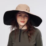 Chapeau de pluie femme imperméable beige à bord large et doublure noire, protection anti-UV élégante pour activités en extérieur.