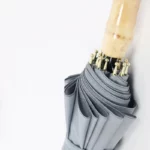 Grand parapluie canne en bambou élégant, gris avec poignée en bois, ouvert, détails dorés raffinés, parfait pour toutes saisons.