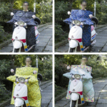 Scooters équipés de tabliers à motifs points blancs, collection colorée, protection pluie sur chemins pavés entourés de verdure.