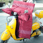 Tablier scooter rouge à pois blancs sur un scooter jaune, parfait pour se protéger des intempéries avec style.