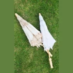 Parapluie enfant en dentelle 60 cm, modèle droit élégant pour mariage, beige et blanc, posés sur une pelouse verte.