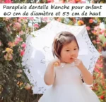 Enfant tenant un parapluie en dentelle blanche 60 cm, idéal pour mariage, dans un jardin fleuri, touche son visage.