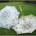 Parapluies enfant en dentelle blanche et crème avec motifs floraux, manche en bois, parfaits pour mariage ou occasions spéciales.