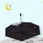 Parapluie enfant voyage dans l'espace, motifs étoiles et lune, sol lunaire, astronaute prenant selfie sur croissant de lune.
