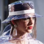 Jeune femme avec chapeau de pluie transparent et imperméable, alliant protection et élégance sous la pluie. Accessoire mode tendance.
