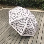 Parapluie beige de luxe automatique avec poignée tête d'ours, design élégant et motifs colorés, idéal pour rester chic sous la pluie.