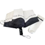 Parapluie blanc bordé de noir anti-UV, élégant et pratique, avec housse assortie, idéal pour protection solaire et style raffiné.