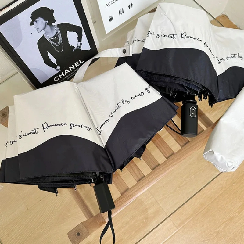 Parapluie blanc bordé de noir anti-UV, design chic et élégant, parfait pour compléter votre style tout en vous protégeant du soleil.