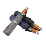 Parapluies golf chic pliés en noir et gris, élégants avec poignées en bois, parfaits pour un style raffiné sur fond blanc.