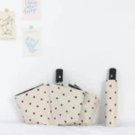 Parapluie blanc à pois noirs anti-UV, automatique ou manuel, design élégant et pratique sur fond minimaliste avec cartes décoratives.