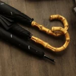Parapluie canne noir élégant avec poignée en bambou naturel, design raffiné et pratique, idéal pour allier style et utilité.