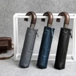 Parapluie de luxe manche en bois, décliné en gris, bleu marine et noir, design élégant, parfait pour les collections automnales.