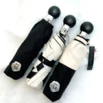 Parapluies de luxe élégants noir, blanc et beige avec motifs chics et poignées florales, alliance de style et protection contre la pluie