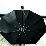 Parapluie de luxe noir et blanc, design moderne, ouvert sur sol décoratif, idéal pour [Collection], élégant et fonctionnel.