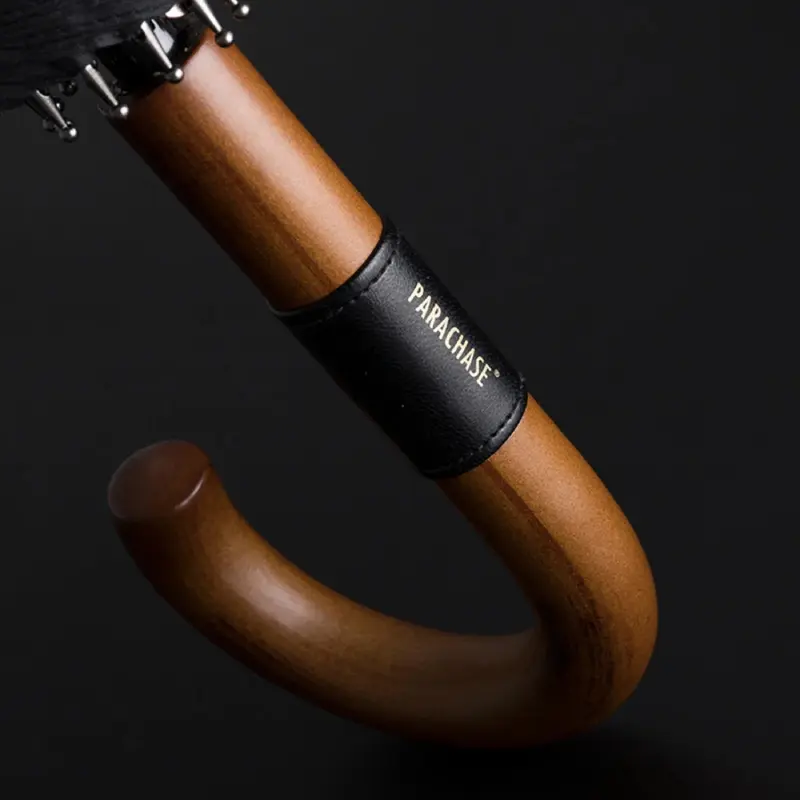 Zoom élégance poignée en bois parapluie luxe PARACHASE vintage, détail anneau noir signé, style raffiné fond sombre.