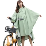 Poncho femme avec poche, collection tendance, idéal pour la pluie, stylé et pratique, femme avec vélo, poncho vert élégant.