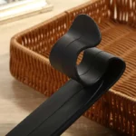 Support parapluie voiture en PVC noir, élégant et pratique, mis en valeur sur fond bois à côté d’une corbeille tressée.