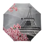 Parapluie élégant avec la Tour Eiffel et un vélo entouré de fleurs roses, parfait pour une allure parisienne chic sous la pluie.