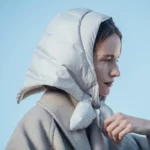 Capuche triangle molletonnée femme hiver, avec nœud élégant, gris moderne, idéale pluie/neige, style chic sous ciel bleu.