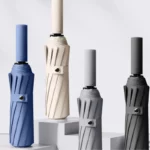 Parapluies anti retournement résistants au vent, design élégant, couleurs variées : bleu, crème, gris clair et gris foncé.